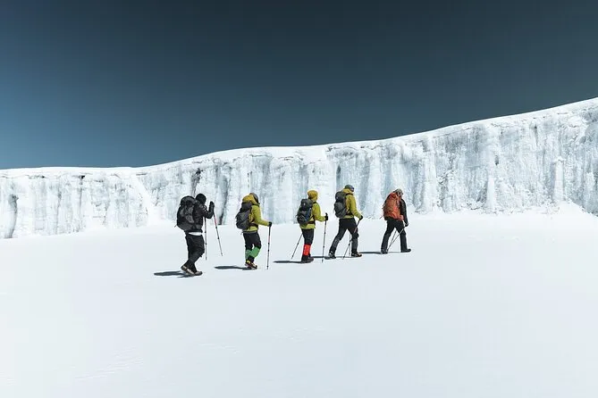 Group of climbers trekking across snow near Kilimanjaro’s ice cliffs.
